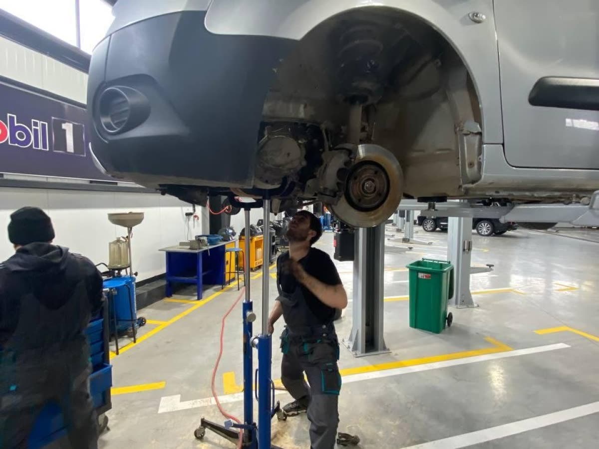 Машина на подъёмнике в цехе Tez Auto, мастер работает под ней
